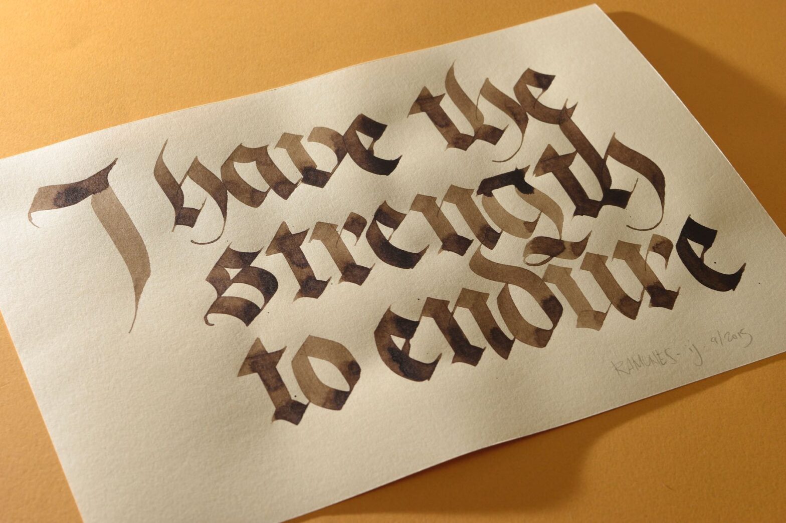 Caligrafia onde se lê “I ha the strength to endure” em papel creme sobre fundo amarelo