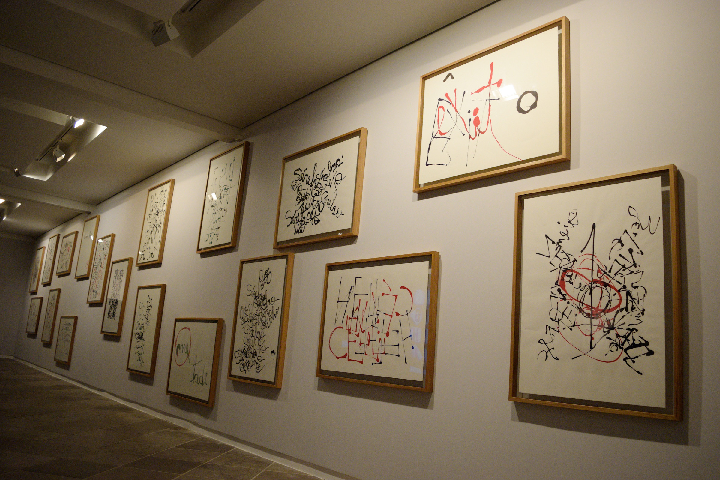 Foto de parede da exposição com quadros da série de caligrafias