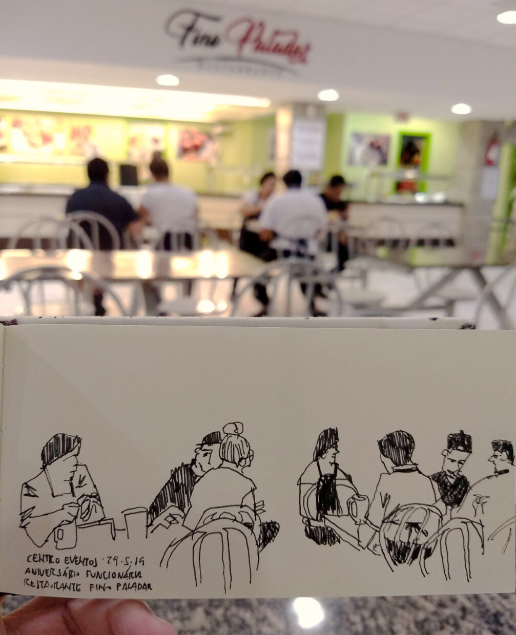 Foto da praça de alimentação do Centro de Eventos da UFSC com funcionários do restaurante Fino Paladar ao fundo e o desenho em primeiro plano