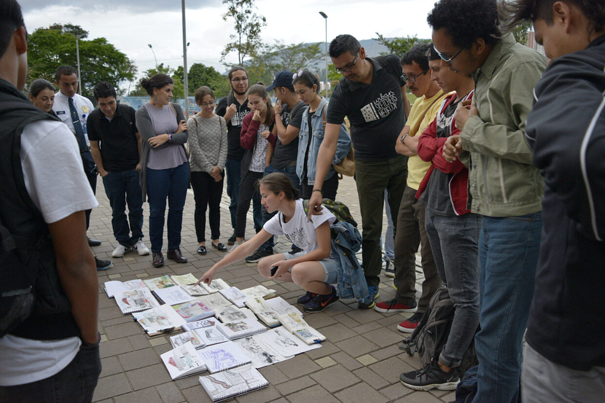Foto mostrando participantes ao redor dos desenhos dispostos no chão