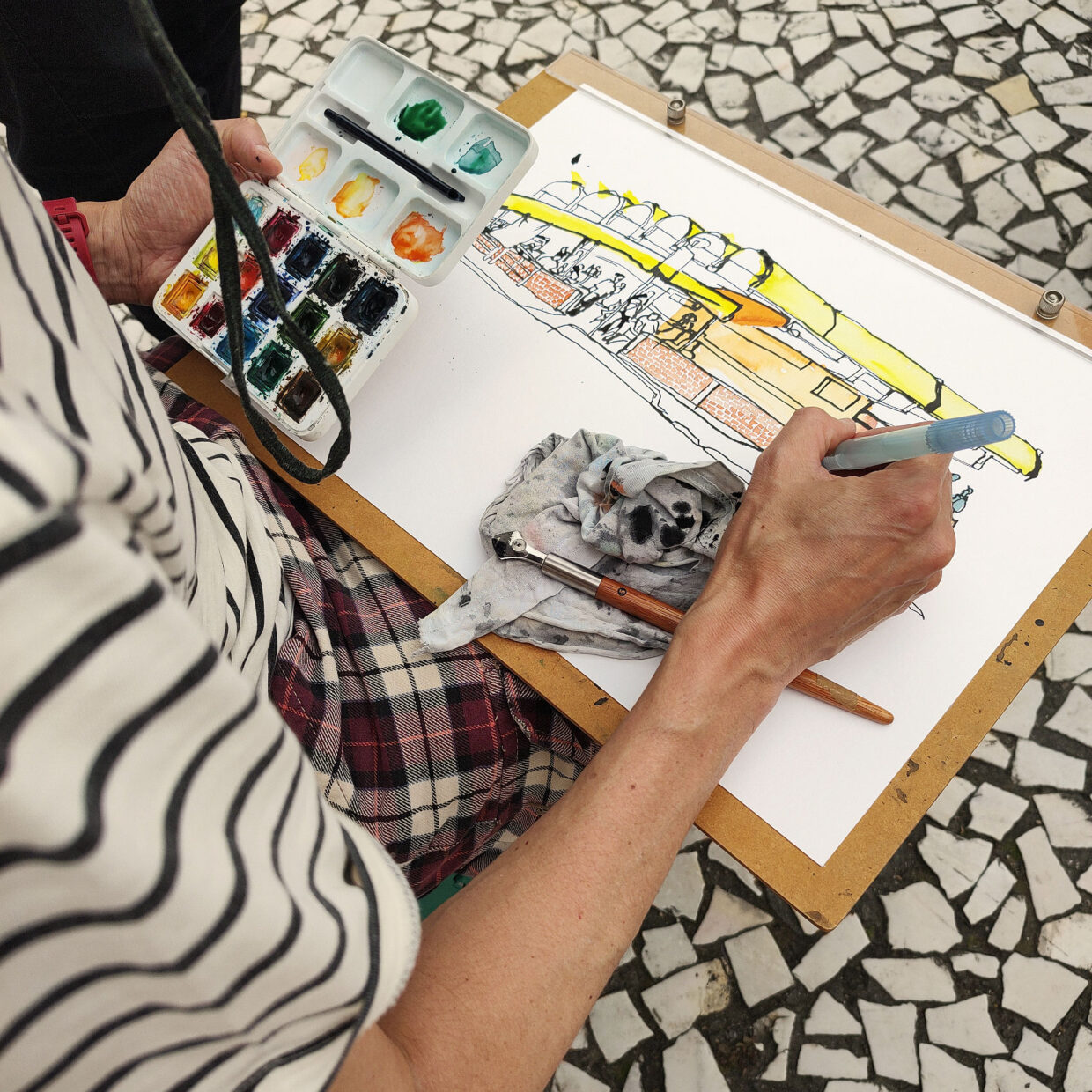 Autor aplica aquarela no desenho apoiado em uma prancheta