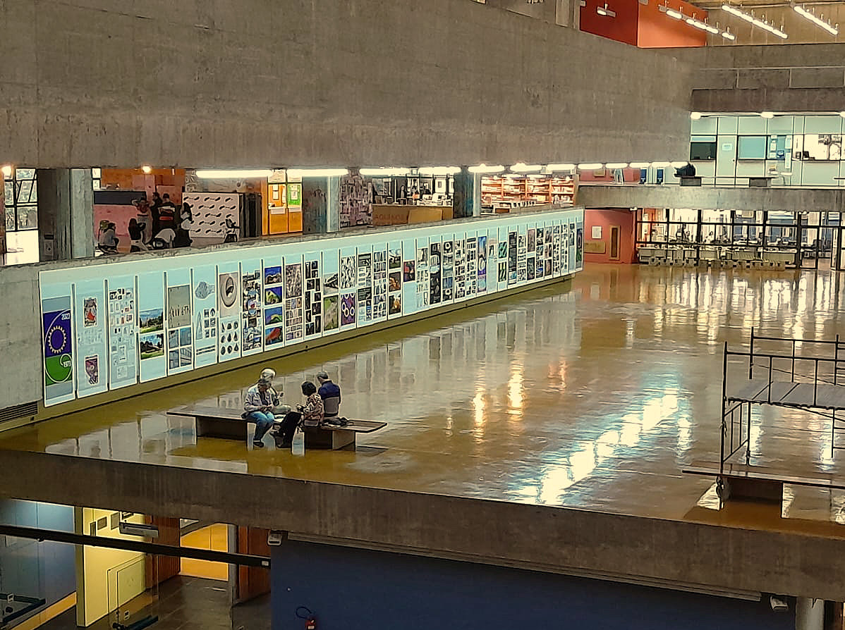 Foto do salão Caramelo da UFSC com uma parede onde estão fixados os banners da exposição