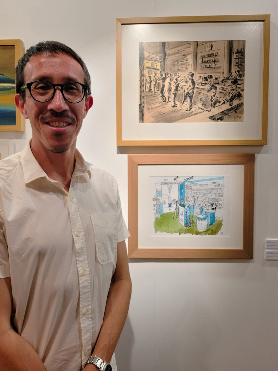 Ivan Jerônimo em frente de dois desenhos na parede – o de Hassis e o seu – na noite de abertura da exposição na Fundação Hassis