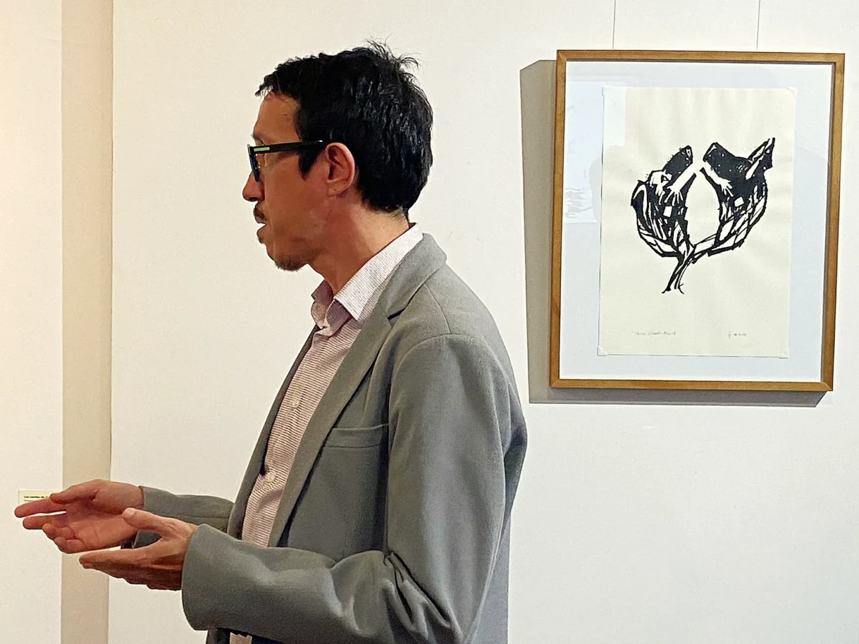 Artista Ivan Jerônimo fala tendo um desenho como fundo na abertura da exposição “Entre as Páginas”